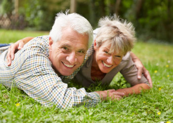 Glückliches Paar Senioren liegt lachend auf einer Wiese im Sommer