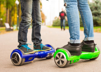 Feet of girl and boy riding electric mini segway outdoors in park. Ecological city transportation on battery power.