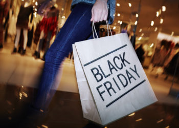 Modern shopper with Black Friday paperbag going in the mall