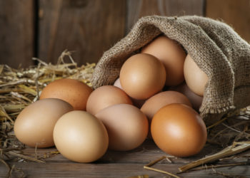 Raw organic farm eggs, straw on the old wooden background